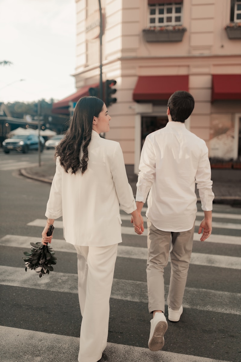 A couple walks across a street holding hands.